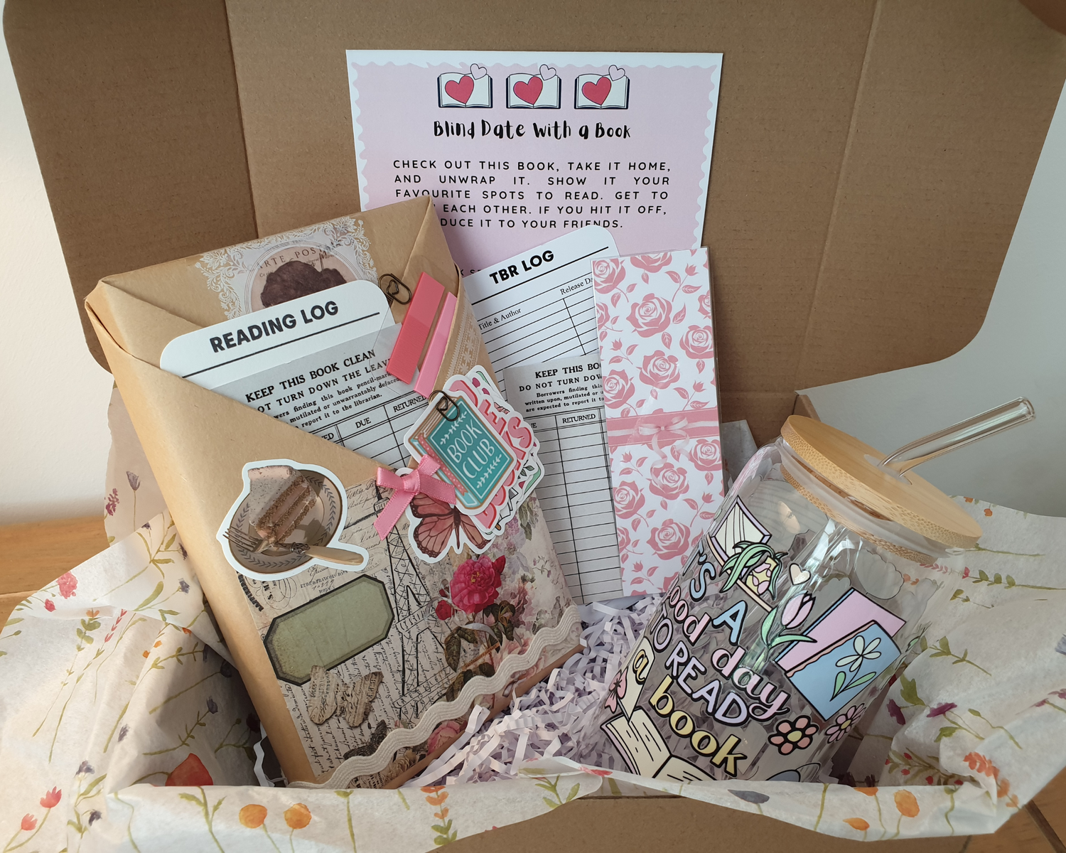 Box containing reading-themed items including a book, reading log, and decorative papers.